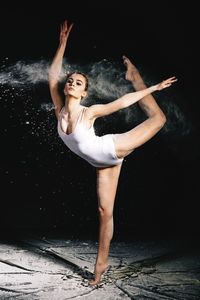 Young woman dancing against black background