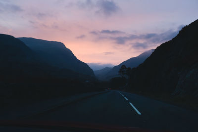 Road amidst mountains against sky during sunset