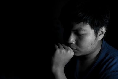 Close-up portrait of teenage boy against black background