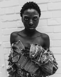 Portrait of young woman standing against wall