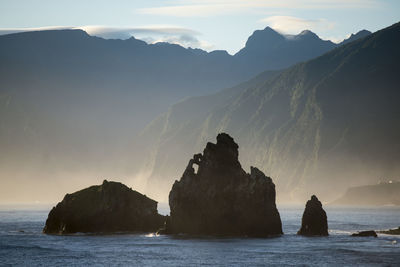 Scenic view of sea and mountains against sky