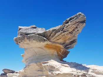 Low angle view of rock formation against blue sky