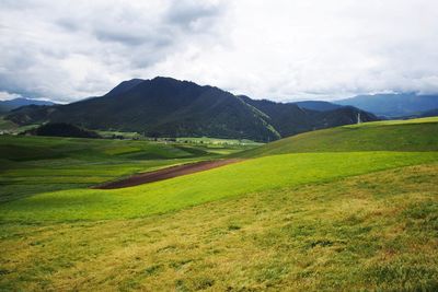 Scenic view of green landscape and mountains against sky