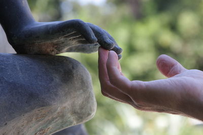 Close-up of man holding statue against blurred background