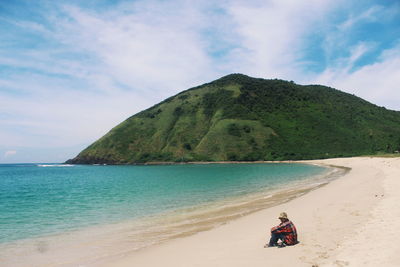 Rear view of man on beach against sky