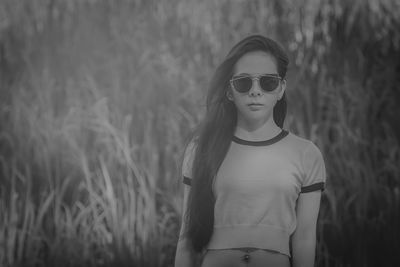 Portrait of young woman wearing sunglasses standing on field