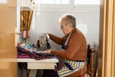 Old lady dressmaker using a sewing machine for some tailor work.