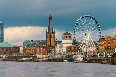 Buildings by river against sky