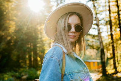 Portrait of young woman wearing sunglasses against trees