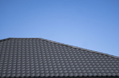 Low angle view of building roof against clear blue sky