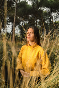 Young woman standing by yellow tree