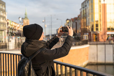 Young woman in jacket traveling with backpack, taking selfie on smartphone camera. travel blogger.