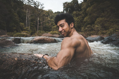 Portrait of shirtless young man on rock