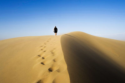 Rear view of a man walking on desert