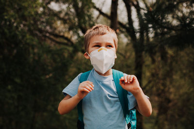 Portrait of boy standing against trees