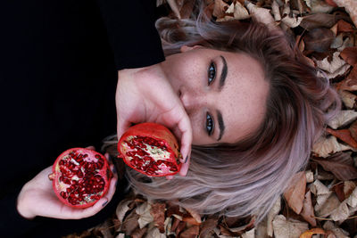 Portrait of young woman holding halved pomegranates