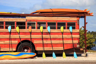 Colorful kayak and paddleboard paddles leaning against a woody style hippy bus in nassau, bahamas.