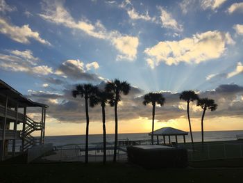 Silhouette palm trees on beach against sky at sunset