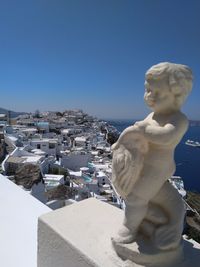 Statue by buildings against clear blue sky