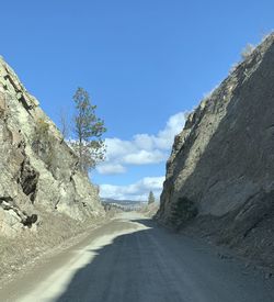 Road amidst mountains against blue sky