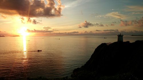 Scenic view of sea against cloudy sky during sunset