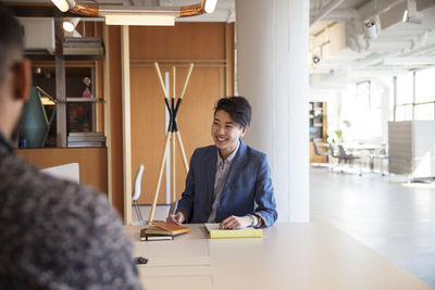 Smiling businesswoman discussing with male coworker in office