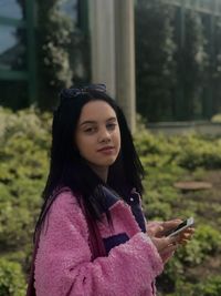 Portrait of young woman standing against trees