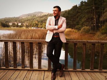 Full length portrait of young man standing against railing