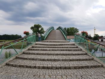 Footpath leading towards bridge against sky