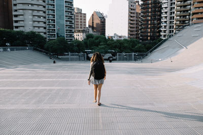 Rear view of woman walking on modern buildings in city