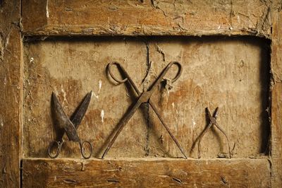 Close-up of rusty scissors and pliers on dirty wooden niche