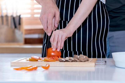 Midsection of person preparing food on cutting board