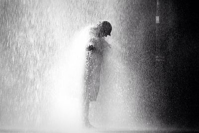 Side view of person standing on street in rainy season