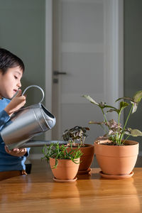 A boy is watering flowers in clay pots.
