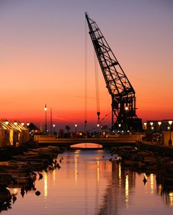 Silhouette of pier at harbor against sky during sunset