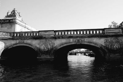 Arch bridge over river against clear sky