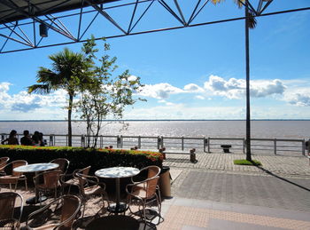 Chairs and tables at cafe against sea