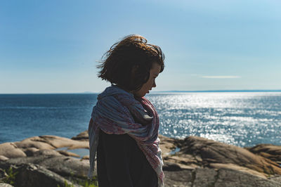 Boy standing at beach against sky