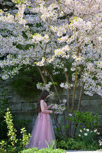 Woman standing by cherry blossom at park