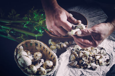 Cropped image of chef peeling mushroom on table