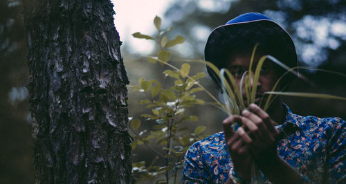 Close-up of woman with flowers on tree trunk