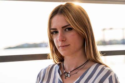 Portrait of young woman standing against railing