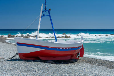 Boat moored on beach against clear sky