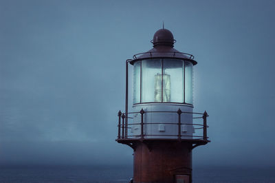 Lighthouse by sea against sky