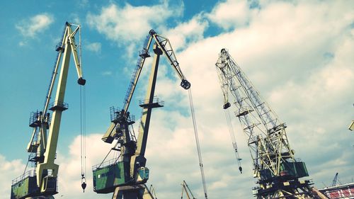 Low angle view of cranes against sky