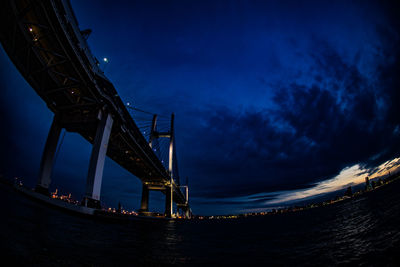 Low angle view of bridge over river against sky at night