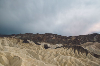 Scenic view of eroded landscape against cloudy sky at death valley national park