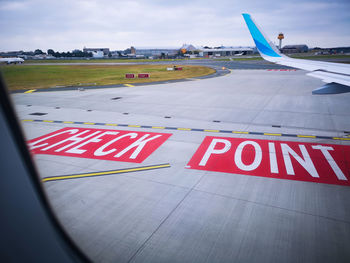 Arrow sign on airport runway against sky
