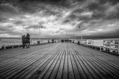 People walking on pier by sea against sky