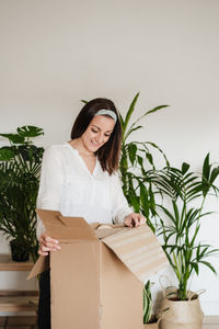 Young woman holding potted plant in box